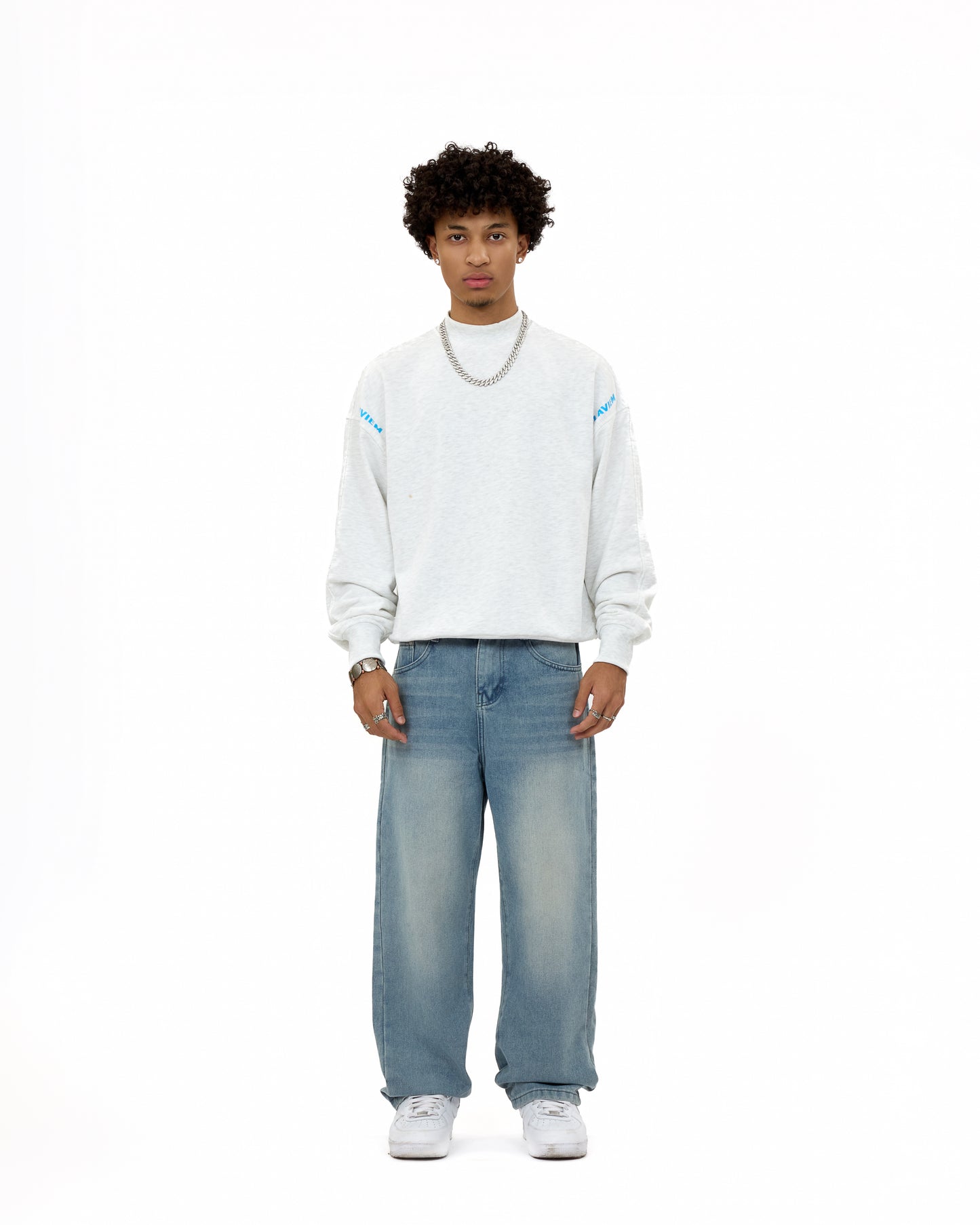 Front view of a male model wearing the LAVIEM Oversized Sweater in grey – a 100% cotton streetwear sweatshirt with a relaxed fit – styled with baggy washed jeans and sneakers for a casual urban menswear look.