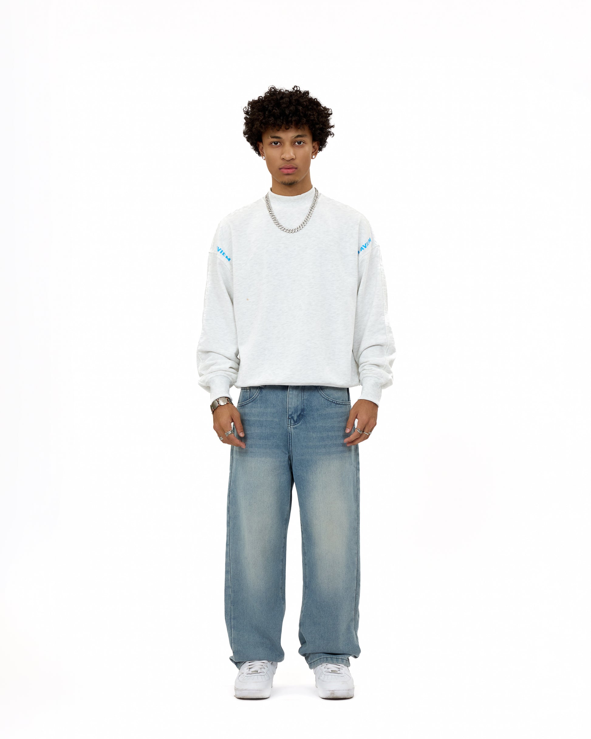 Front view of a male model wearing the LAVIEM Oversized Sweater in grey – a 100% cotton streetwear sweatshirt with a relaxed fit – styled with baggy washed jeans and sneakers for a casual urban menswear look.