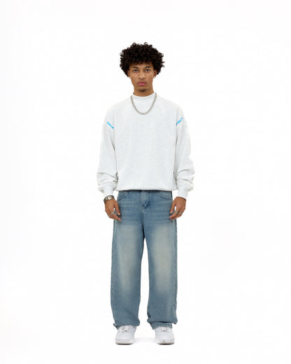Front view of a male model wearing the LAVIEM Oversized Sweater in grey – a 100% cotton streetwear sweatshirt with a relaxed fit – styled with baggy washed jeans and sneakers for a casual urban menswear look.