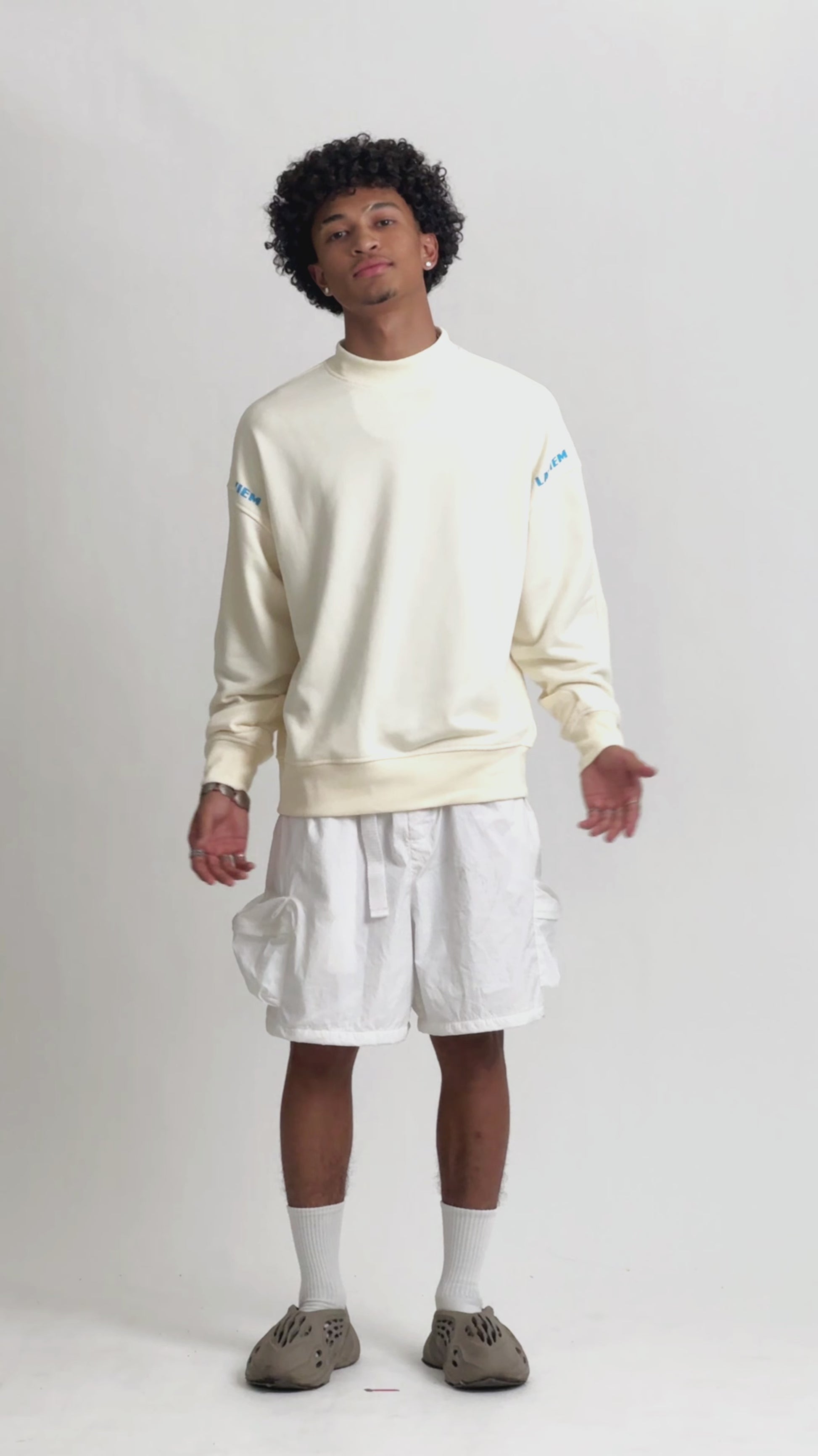 Video of a male model showcasing the LAVIEM Oversized Sweater, a 100% cotton streetwear sweatshirt with a relaxed, boxy fit. It highlightes the sweater’s drape and comfort, styled with baggy jeans, cargo shorts and white sneakers for an urban menswear look.